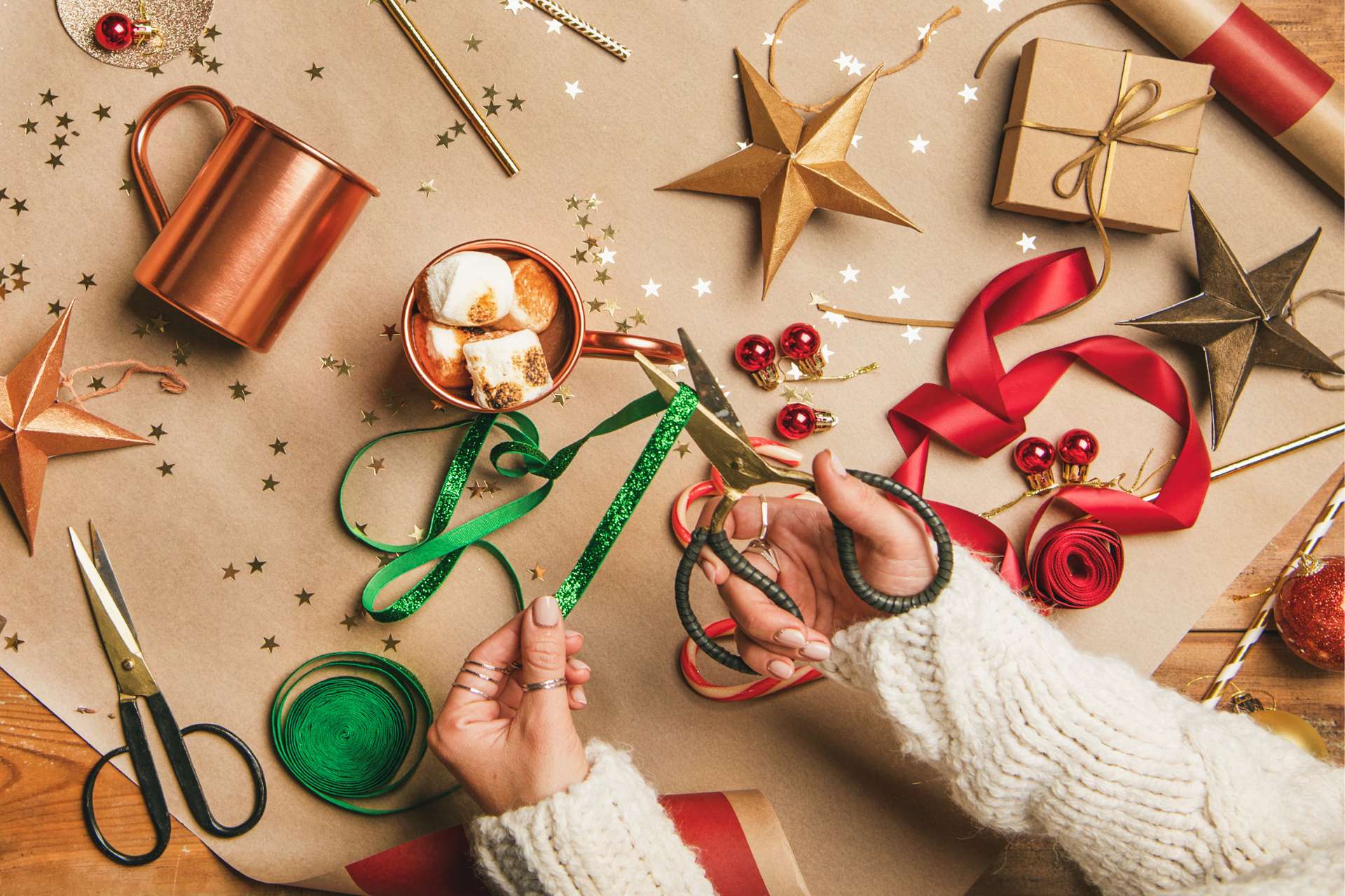 A table with craft paper, glitter, Christmas ribbon, and hot coco