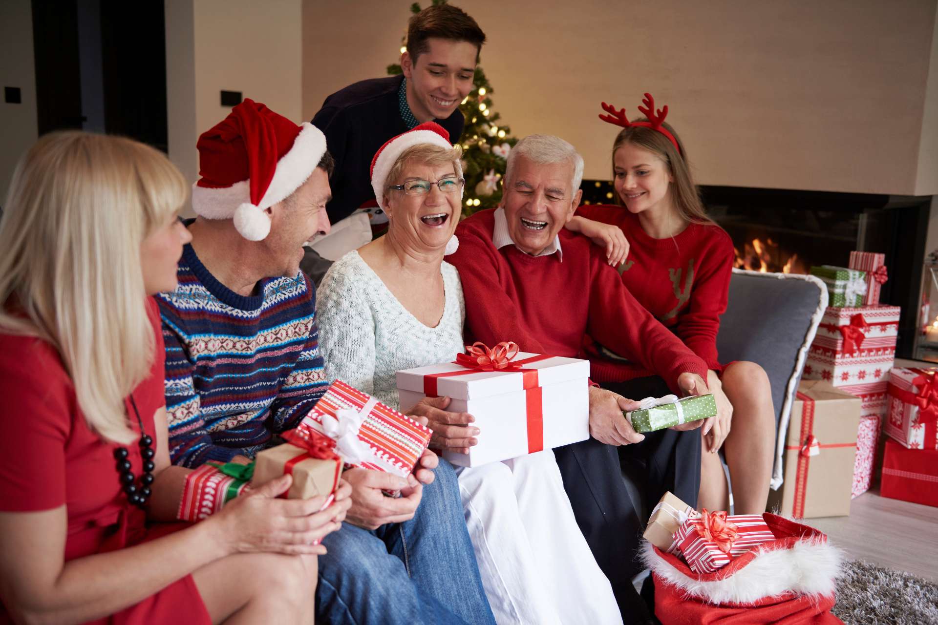 A group of seniors wearing Christmas clothes and exchanging gifts.